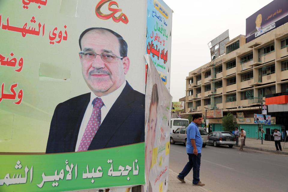 FILE - In this file photo taken on April 27, 2014 people pass by a campaign poster of Iraqi Prime Minister Nouri al-Maliki in Baghdad, Iraq. If Iraqi Prime Minister Nouri al-Maliki wins a third four-year term in parliamentary elections Wednesday, he is likely to rely on a narrow sectarian Shiite base, only fueling divisions as Iraq slides deeper into bloody Shiite-Sunni hatreds. (AP Photo/Karim Kadim, File)
