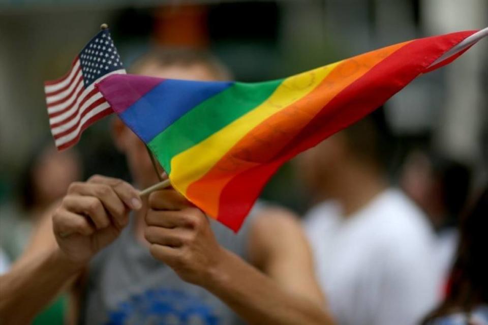 A protester holds an American flag and a rainbow flag in front of the Miami-Dade Courthouse in Florida in 2014 to in support of LGBTQ couples.