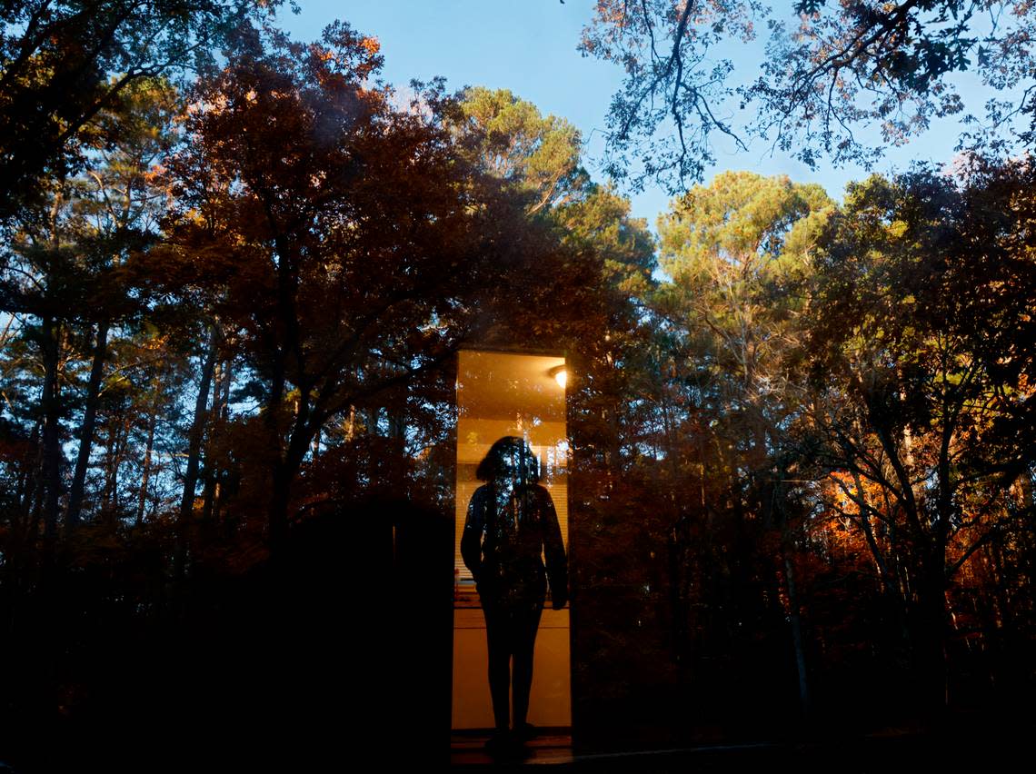 Sheba Everett walks inside as autumn foliage reflects in the front door of her Durham, N.C. home on Thursday, Nov. 3, 2022. Everett, who for two years has rented the house where she lives with her five daughters, received an eviction letter after the Eno River Association planned to transfer the land to the state park system.