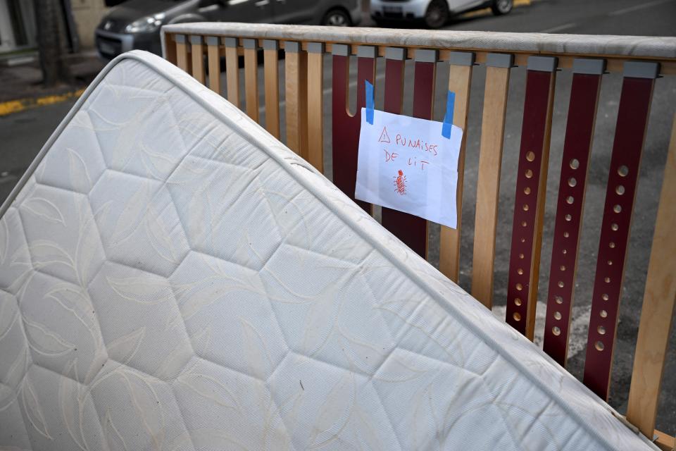 A sign reading "bed bugs" looms above a mattress abandoned in Marseille.