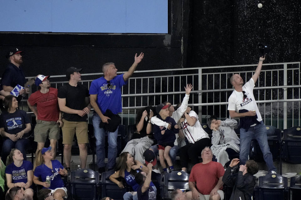 Fans try to catch a solo home run ball hit by Atlanta Braves' Sean Murphy during the fifth inning of a baseball game against the Kansas City Royals Friday, April 14, 2023, in Kansas City, Mo. (AP Photo/Charlie Riedel)