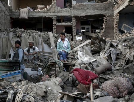 Men sit amid debris of their properties at the site a truck bomb blast in Kabul, August 7, 2015. REUTERS/Ahmad Masood