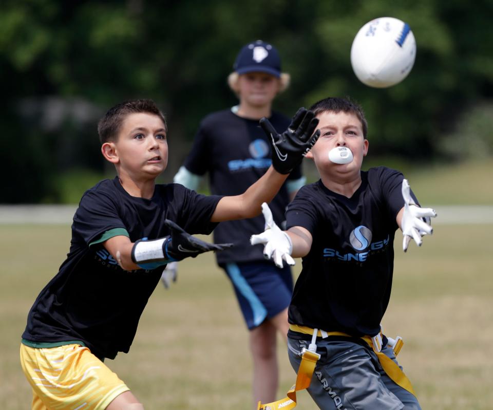 Kian Wosnig and James Sperber, both 10, try to make the catch during a Howard-Suamico Youth Flag Football practice on Friday at Idlewild Park in Suamico before the NFL FLAG Football regional tournament at the Green Bay Packers' Ray Nitschke Field.