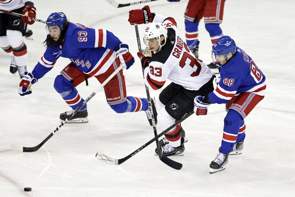 New Jersey Devils defenseman Ryan Graves (33) battles for the puck between New York Rangers right wing Patrick Kane (88) and Mika Zibanejad (93) in the third period of Game 3 of the team's NHL hockey Stanley Cup first-round playoff series Saturday, April 22, 2023, in New York. (AP Photo/Adam Hunger)