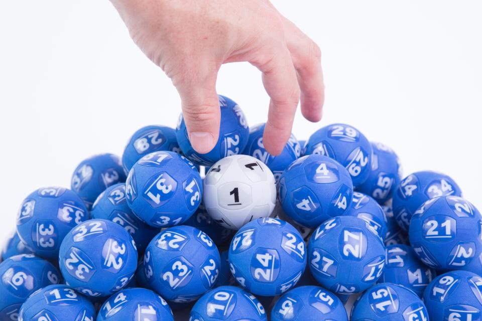 A man picks up a Powerball ball in a pile of lottery balls.