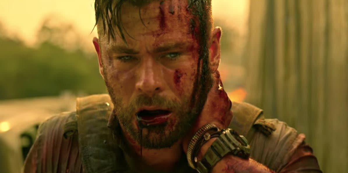 chris hemsworth holds his neck after being shot in netflix movie extraction