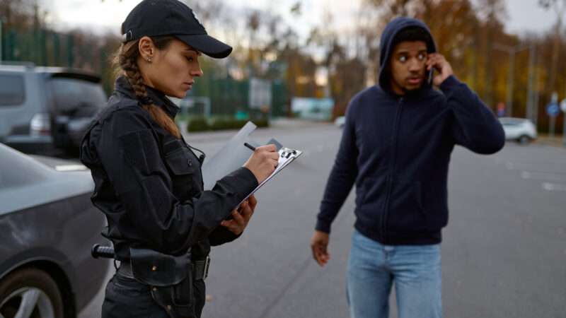 A female police officer writes a ticket for a male motorist.