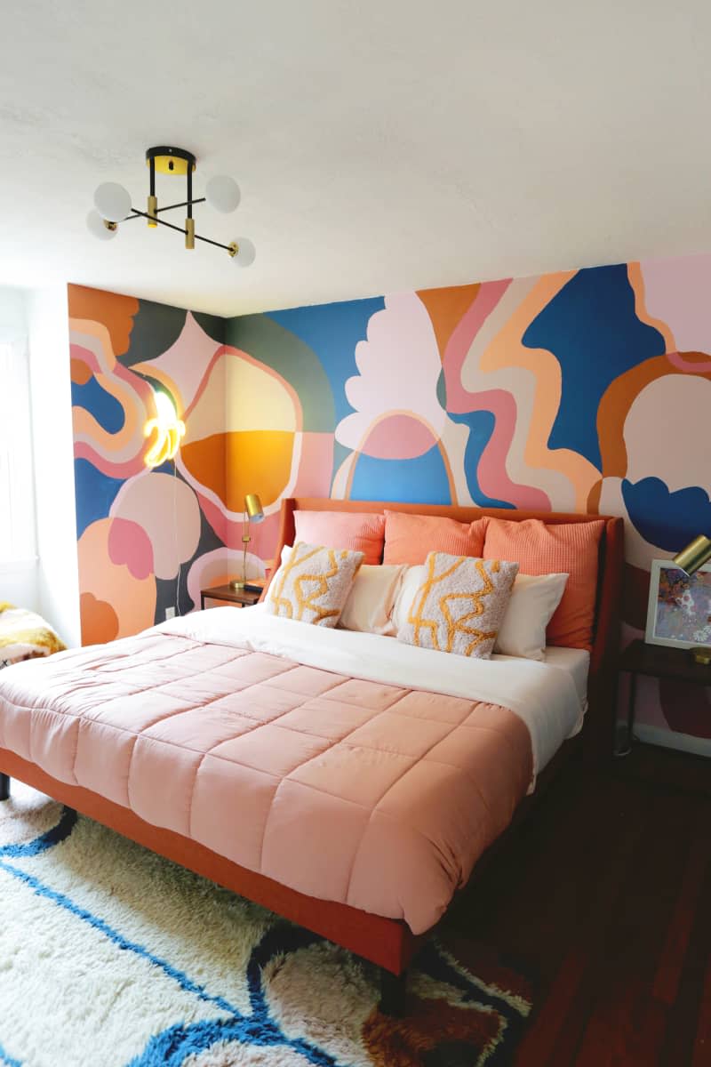Colorful mural painted in bedroom with neatly made bed with pink bedding.