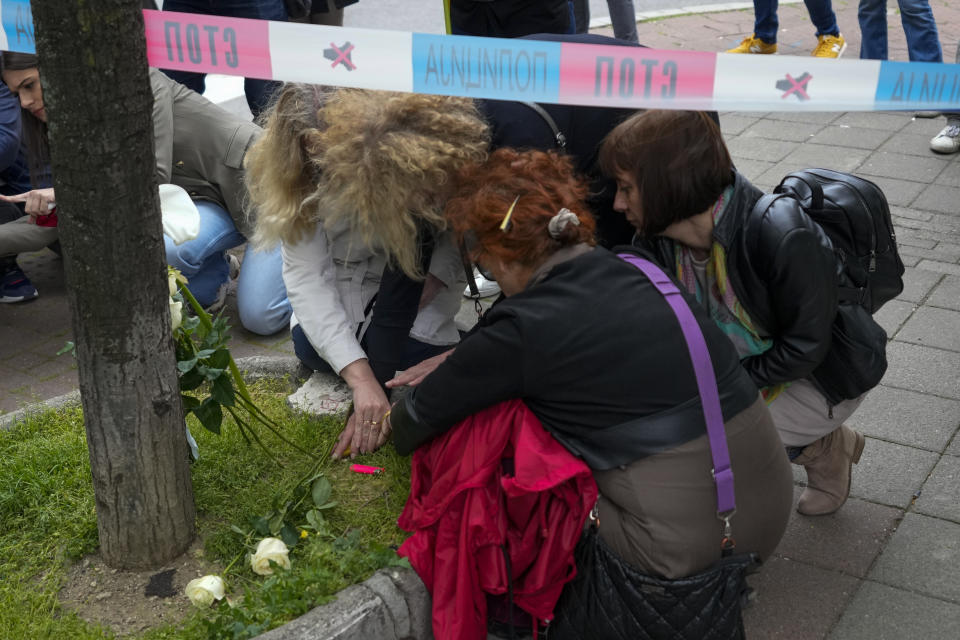 Women lay flowers and light candles for victims near the Vladislav Ribnikar school in Belgrade, Serbia, Wednesday, May 3, 2023. A 13-year-old who opened fire Wednesday at his school in Serbia's capital drew sketches of classrooms and wrote a list of people he intended to target in a meticulously planned attack, police said. (AP Photo/Darko Vojinovic)