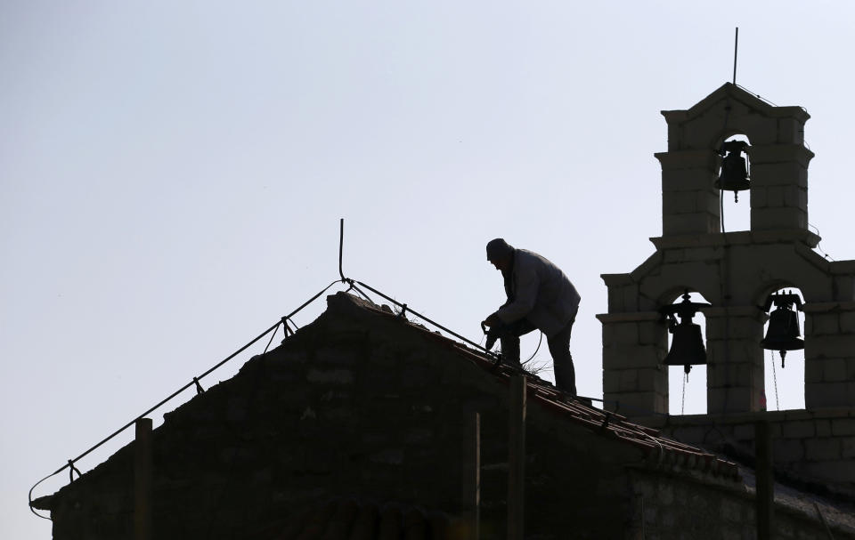In this Wednesday, March 15, 2017 file photo, a worker fixes roof on Holy Sunday church in the 'Tsar's Village' complex near Sveti Stefan peninsula in Montenegro. A Serb official has branded Montenegro a "criminal" state and threatened a "fierce" response over the neighboring country's plans to introduce a church law. The draft law calls for all religious communities in Montenegro to provide proof that they owned their property before 1918 when the small Adriatic state lost its independence and became part of the Serb-dominated Kingdom of Serbs, Croats and Slovenes. If they don't, the property becomes state owned. (AP Photo/Darko Vojinovic, File)
