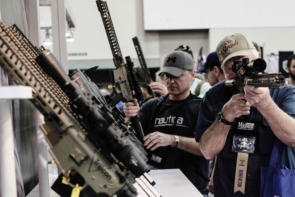 National Rifle Association convention guests inspect rifles in Indiana on 14 April, 2023. (AFP via Getty Images)