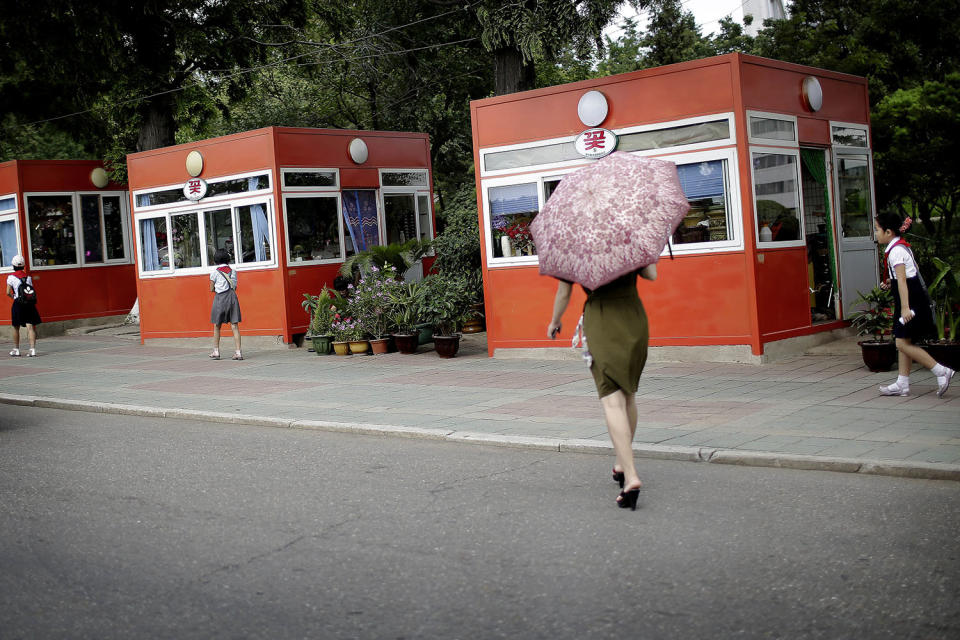 <p>A woman carries a parasol as she walks toward kiosks that sell flowers, snacks and drinks on July 18, 2017, in Pyongyang, North Korea. (Photo: Wong Maye-E/AP) </p>