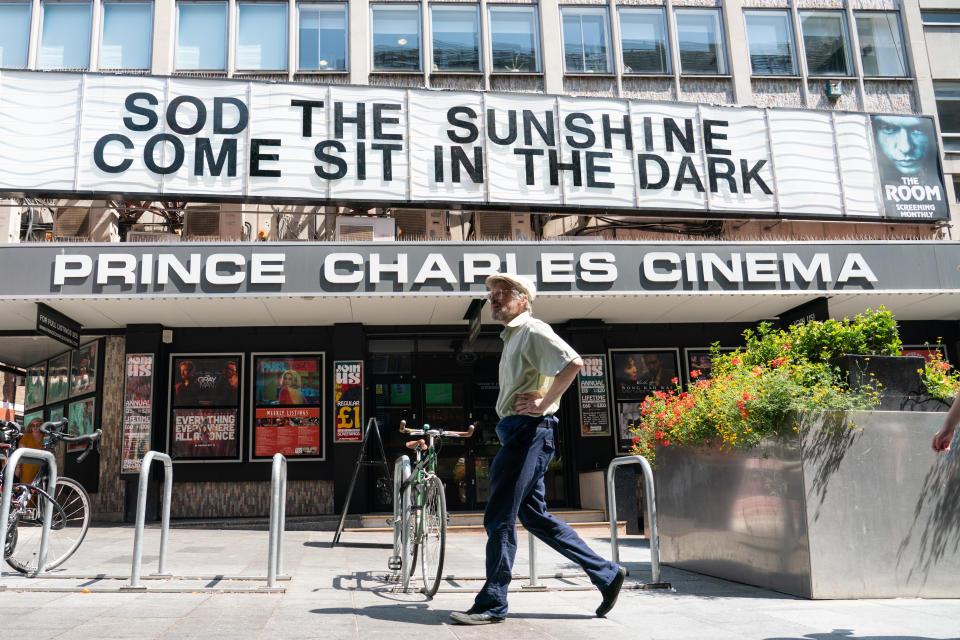 A man walks past a movie theater in central London.