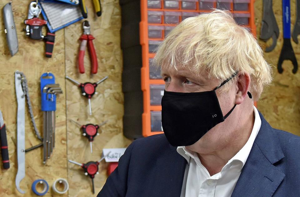 Britain's Prime Minister Boris Johnson wearing a black face mask featuring a number '10', due to the COVID-19 pandemic, talks to the owner of the the Cycle Lounge, Rodney Rouse, a bicycle repair shop in Beeston, central England, on July 28, 2020, during an event to launch the the government's new cycling intuitive to help get people fitter. - The British government promised Monday to build thousands of miles of new bike lanes to get people moving and healthy after months of coronavirus lockdown. Prime Minister Boris Johnson's pledge comes on the heels of a plan to force restaurants to display calories on menus as part of a broader effort to win the battle of the bulge. (Photo by Rui Vieira / POOL / AFP) (Photo by RUI VIEIRA/POOL/AFP via Getty Images)