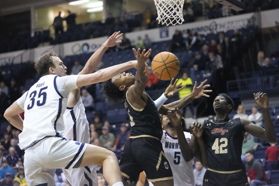 Monmouth forward Klemen Vuga (35) stops College of Charleston forward Raekwon Horton, center, from scoring during the first half an NCAA college basketball game, Thursday, Jan. 19, 2023, in West Long Branch, N.J. (AP Photo/Mary Altaffer)