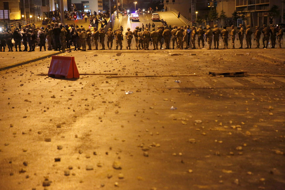 Lebanese army soldiers stand guard as a clash erupted between supporters of the Shiite Hezbollah and Amal groups and the anti-government protesters, in Beirut, Lebanon, early Monday, Nov. 25, 2019. Security forces fired tear gas amid confrontations in central Beirut that went into Monday morning between Hezbollah supporters and demonstrators protesting against Lebanon's political elite. (AP Photo/Hussein Malla)