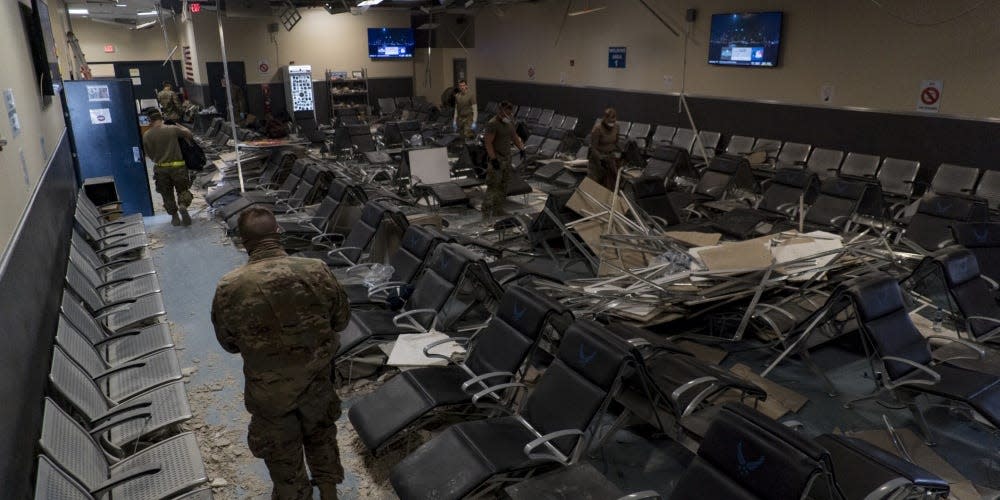 U.S. Air Force Airmen from the 405th Expeditionary Support Squadron work together to clear debris inside the passenger terminal the day after a Taliban-led attack at Bagram Airfield, Afghanistan, Dec. 12, 2019.