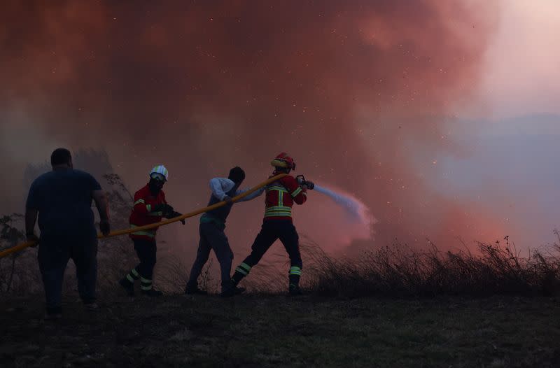 A firefighter and locals try to extinguish a wildfire in Cascais