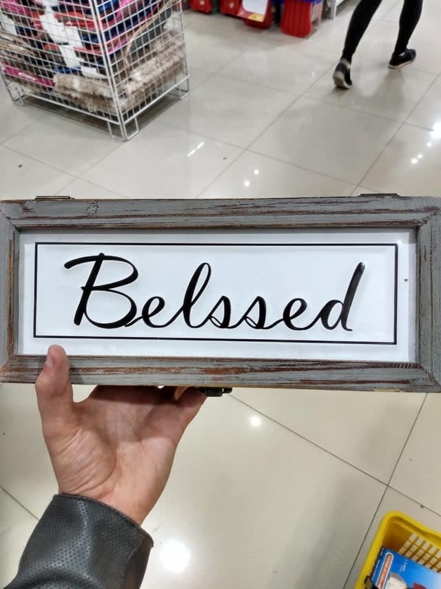 Hand holding a sign with the misspelled word "belssed" in a store