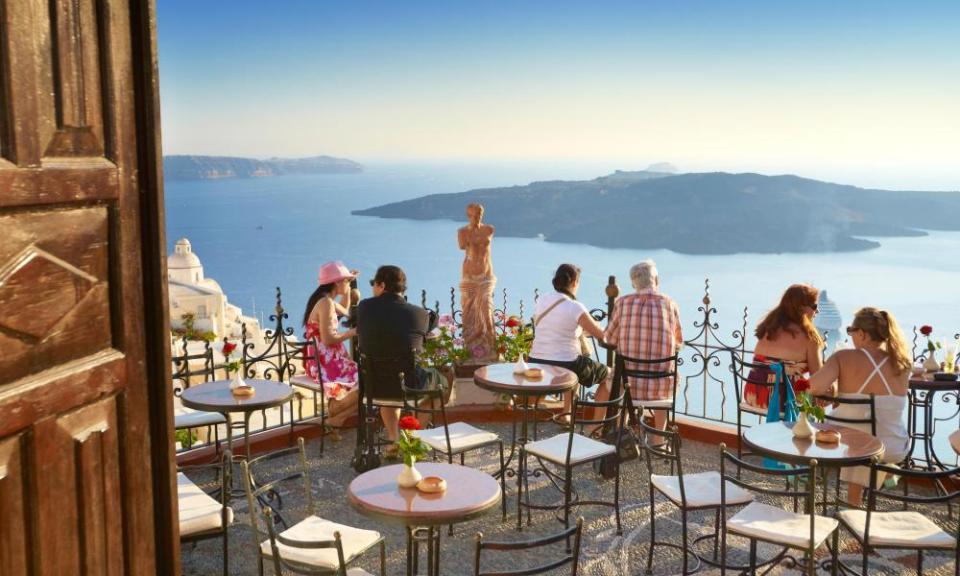 Thira (capital of Santorini) - tourists resting on the greek cafe restaurant terrace, Santorini Island, Greece