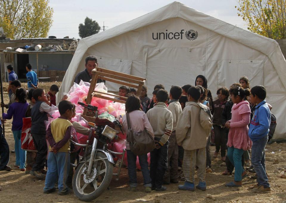 Syrian refugee children gather around a street vendor at a Syrian refugee camp in the Bekaa Valley