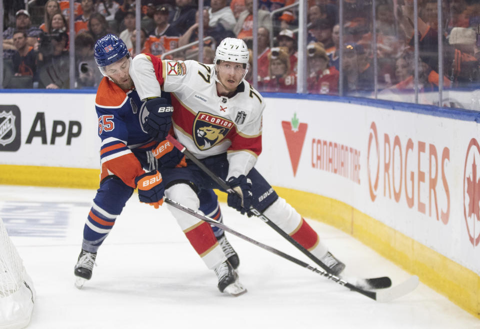 Florida Panthers' Niko Mikkola (77) and Edmonton Oilers' Dylan Holloway (55) vie for the puck during the second period of Game 4 of the NHL hockey Stanley Cup Final, Saturday, June 15, 2024, in Edmonton, Alberta. (Jason Franson/The Canadian Press via AP)