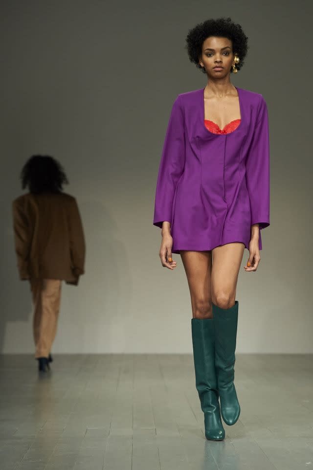 A mini-dress revealing a brightly colored bra at Marta Jakubowski, matched with knee boots for a sexy, retro style. London, February 16, 2018