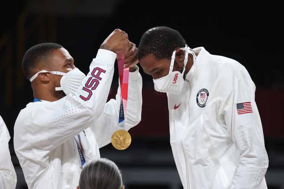 Damian Lillard, left, presents teammate Kevin Durant with his gold medal following Team USA's win over France at the Tokyo Olympics.