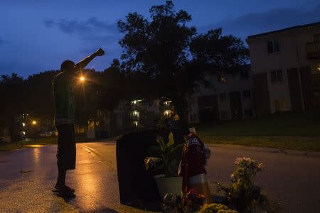 A local resident stands with his arm up over a makeshift memorial at the site where unarmed teen Michael Brown was shot dead in Ferguson, Missouri August 27, 2014. REUTERS/Adrees Latif