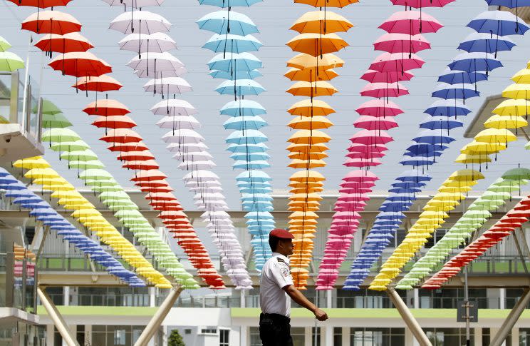 A security guard walks under the floating umbrella decorations at commercial business park in Rawang outside Kuala Lumpur, Malaysia, March 19, 2017. (AP Photo/Daniel Chan)