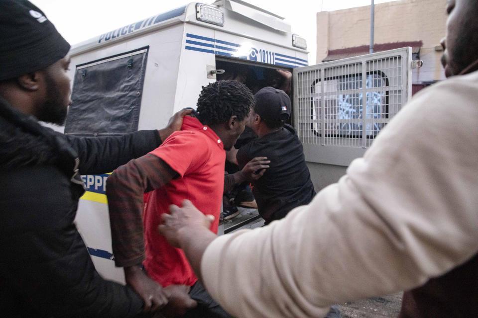 In this Monday, Sept. 2, 2019, photo, looters are arrested by police and foreign nationals outside their shop in Troyville, Johannesburg. Looting and violence spread across several neighborhoods in South Africa's major cities of Pretoria and Johannesburg after a spate of attacks that appeared to target foreign-owned shops. (AP Photo)