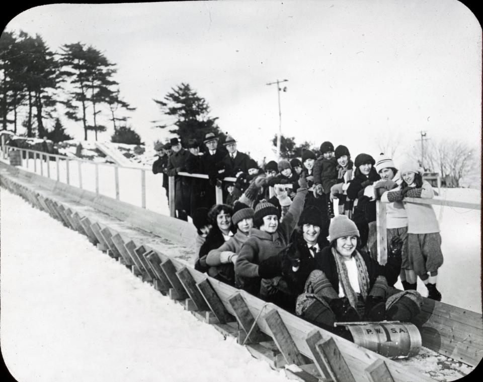 The initials P.W.S.A. on this toboggan likely stand for the Portsmouth Winter Sports Association, which in 1924 built and opened a toboggan chute at The Pines off South Street. The men standing in the background may be members of the Portsmouth Chamber of Commerce.