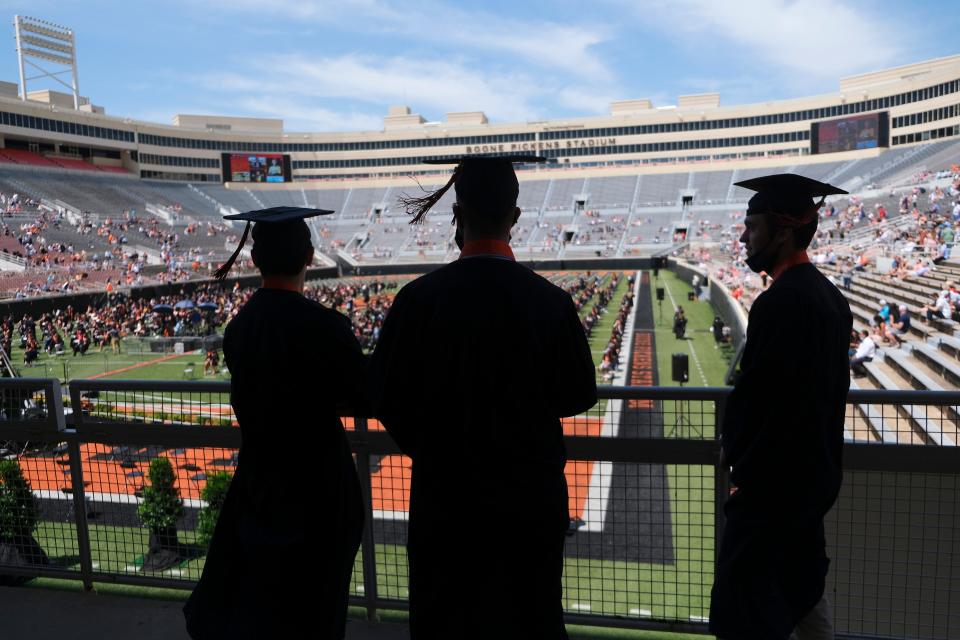 Three graduates arrive at Oklahoma State University's May 8, 2021, graduation ceremony, which honored the Class of 2020 and 2021, at Boone Pickens Stadium in Stillwater.