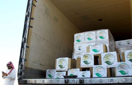 A saudi man uses his mobile as he stands next to a truck loaded with aid offered by King Salman Center for Relief and Humanitarian Aid to be sent to the Yemeni people, in Riyadh, April 17, 2016. REUTERS/Faisal Al Nasser