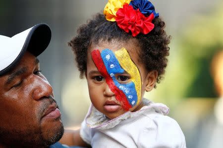 An opposition supporter holds a girl with her face painted in the national colours after an unofficial plebiscite against President Nicolas Maduro's government and his plan to rewrite the constitution, in Caracas, Venezuela July 16, 2017. REUTERS/Christian Veron