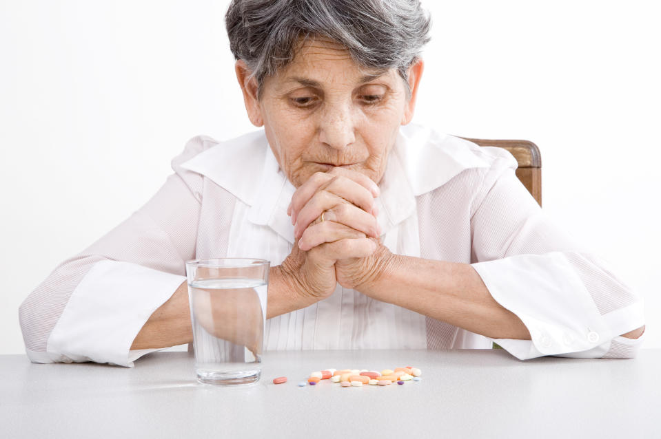 An older patient contemplates taking her medicine