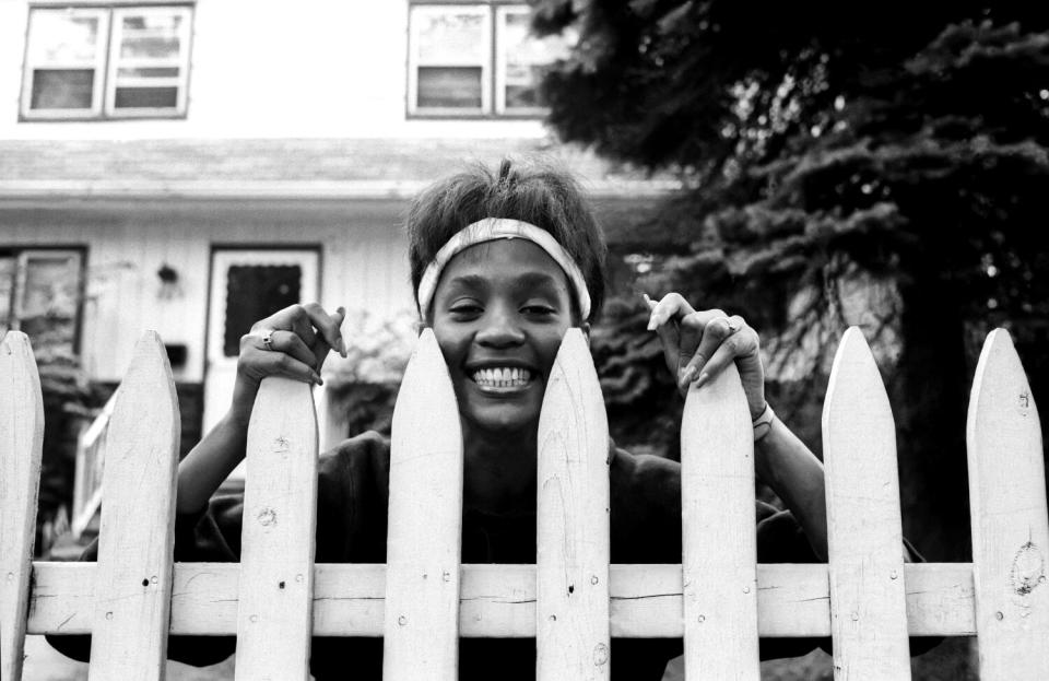 A young woman looks over a picket fence.