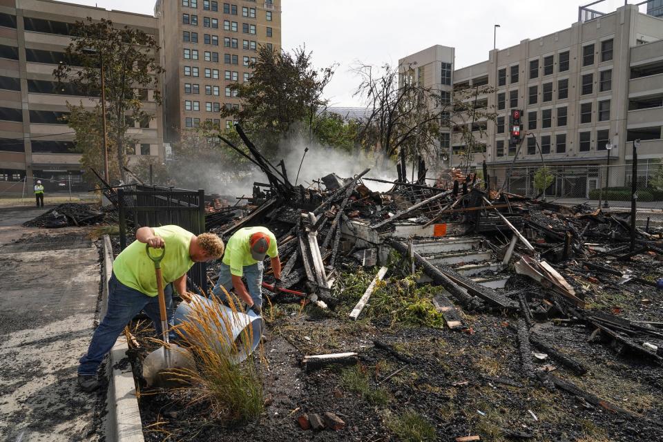 Workers dump debris shoveled from a parking lot while cleaning up after the two-story wood house, at 2712 Cass Ave. in Detroit, whose owner is one of the last arena district "holdouts" who has not sold their property to the Ilitch family organization, caught fire early Monday morning destroying the building.