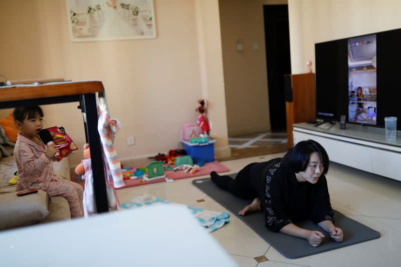 Zhang Kefei exercises next to her daughter Cai, following a class being livestreamed, at their house, as the country is hit by an outbreak of the new coronavirus, in Beijing