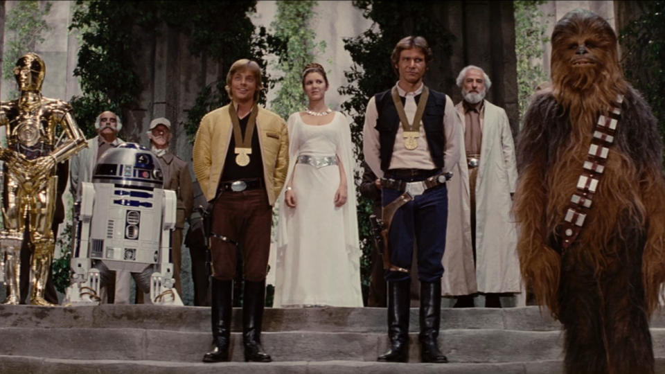 Mark Hamill Carrie Fisher and Harrison Ford stand in the throne room in Star Wars: A New Hope.