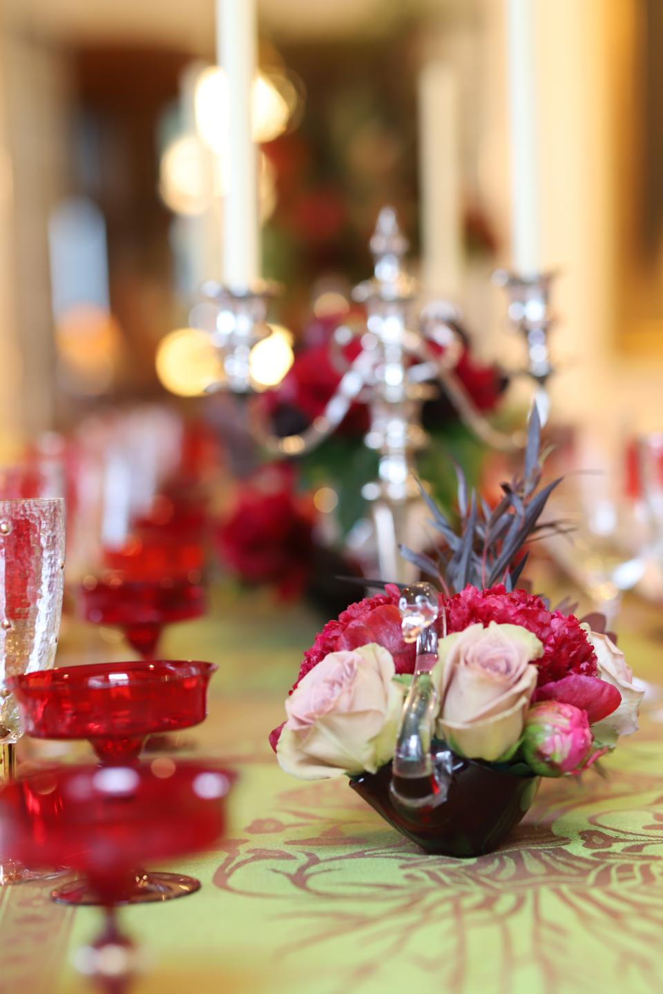 This photo provided by interior designer Elizabeth Stuart shows some centerpieces she created on a table in a residence in Charleston, S.C. Don’t feel obligated to stick to a palette of only red and green for Christmas table decoration, says Stuart. She created the petite centerpieces shown here using pink roses, rather than red. (Travis Drew/Elizabeth Stuart via AP)