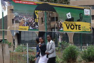 People walk past torn billboards of Zimbabwean President Robert Mugabe's Zimbabwe African National Union - Patriotic Front (ZANU-PF) in Harare, Zimbabwe November 19, 2017. REUTERS/Philimon Bulawayo