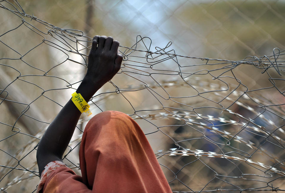 A newly registered Somali refugee supports herself on a chain-link perimeter fence outside a registration and medical aid facility at the Dadaab Internally Displaced People (IDP) camp in eastern Kenya on July 23, 2011 where the influx of Somali's displaced by a ravaging famine remains high.&nbsp;