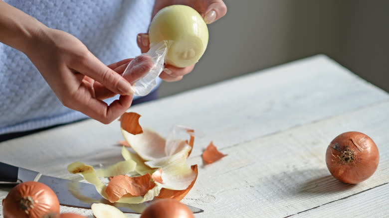 Woman pulling skin off onion 