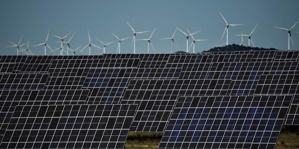 This photograph shows photovoltaic solar panels and windmills in the background around the Spanish Navarre town of Milagro on April 5, 2023.