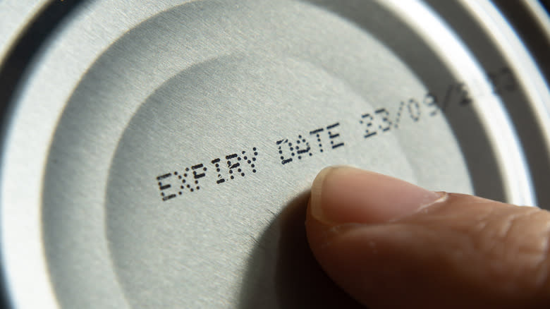 finger pointing to expiration date on can