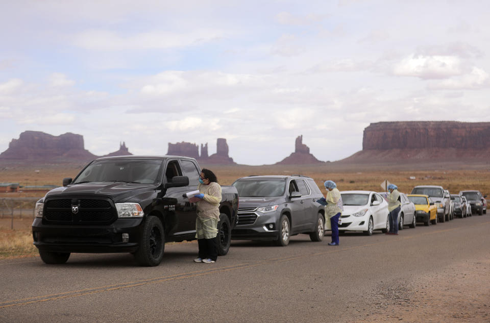 FILE - Korene Atene, a certified nursing assistant with the Monument Valley Health Center, gets information from people lined up to get tested for COVID-19 outside of the center in Oljato-Monument Valley, San Juan County, on Thursday, April 16, 2020. In a pandemic that has seen sharp divides between urban and rural vaccination rates nationwide, Arizona is the only state where rural vaccine rates outpaced more populated counties, according to a recent report from the U.S. Centers for Disease Control and Prevention. (Kristin Murphy/The Deseret News via AP, File)