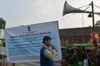 An Indian health worker speaks next to a banner durign a coronavirus information camp for travellers at an India-Nepal border crossing in Siliguri.