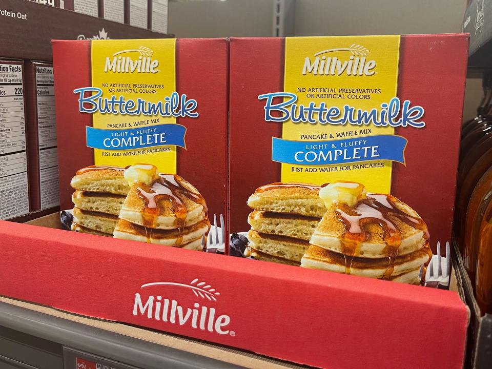 Two red and yellow boxes of pancake mix in a display