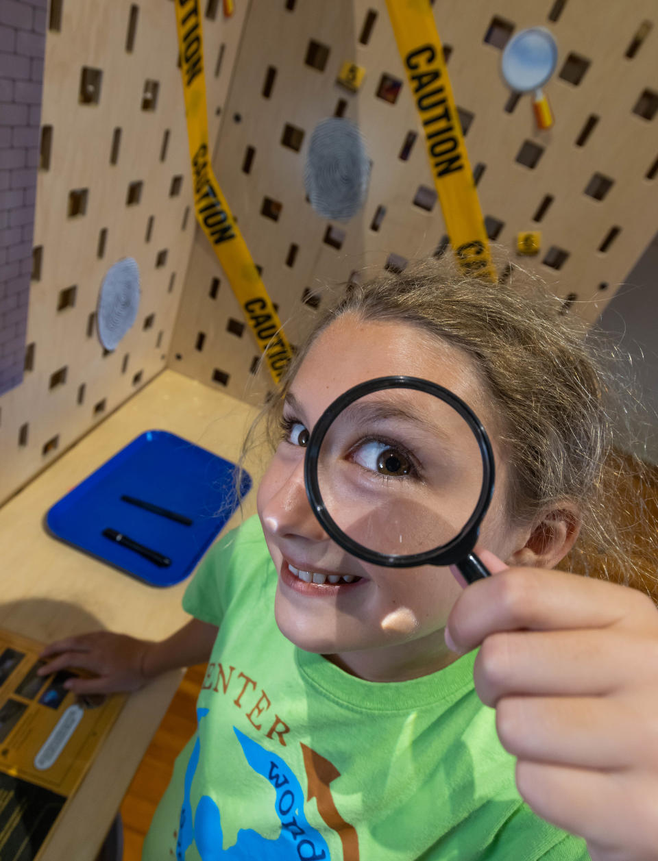 Violet Messenger, 10, checks out a magnifying glass in the fingerprint station in the "Spy Science" exhibit at the Discovery Center in Ocala.